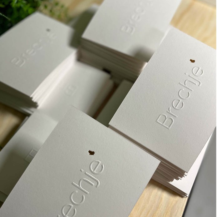 Minimalistisch geboortekaartje met reliëfdruk en goudfolie vlinder