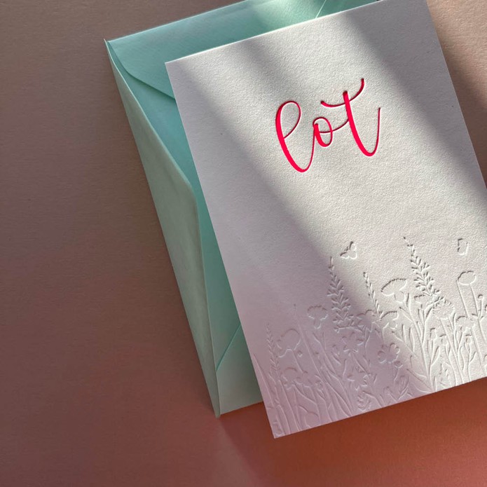 Romantisch geboortekaartje met bloemen veld in blinde druk en sierlijke naam van roze folie