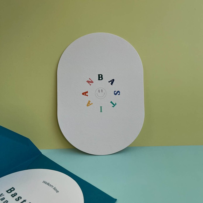 Ovaal geboortekaartje, beige met gekleurde hoogglans letters