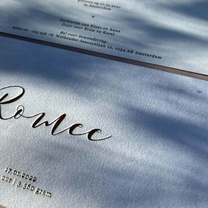 Klassiek geboortekaartje op suede stof met sierlijke letters in luxe goudfolie