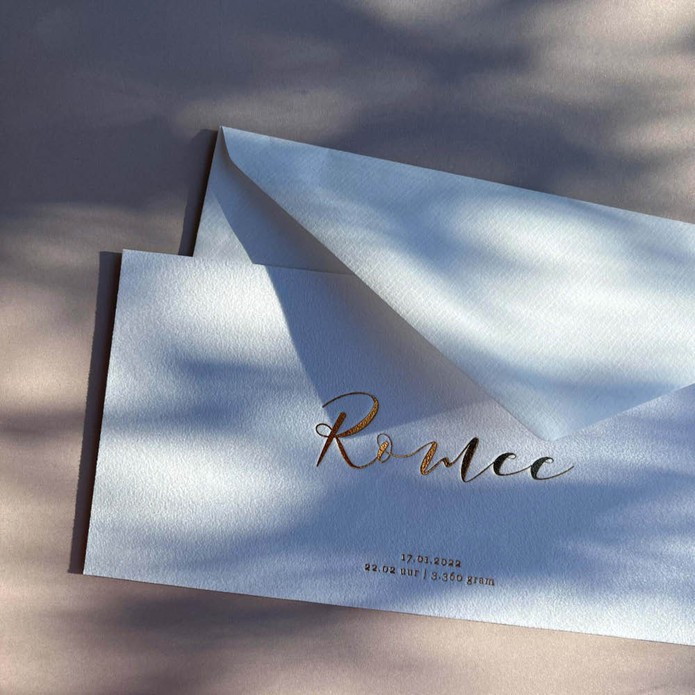 Klassiek geboortekaartje op suede stof met sierlijke letters in luxe goudfolie