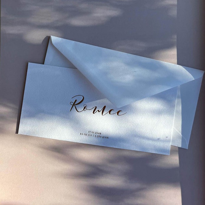 Klassiek geboortekaartje op suede stof met sierlijke letters in luxe goudfolie